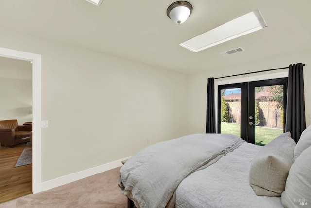 carpeted bedroom with visible vents, baseboards, a skylight, french doors, and access to outside