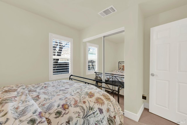 bedroom with visible vents, baseboards, light colored carpet, and a closet