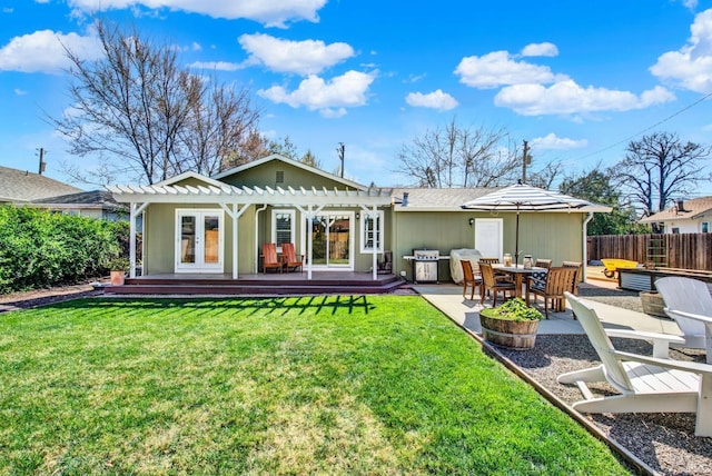 rear view of property with fence, a pergola, french doors, a deck, and a lawn