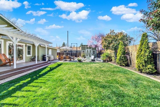 view of yard with an outbuilding, a patio, a fenced backyard, a deck, and a storage shed