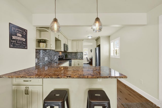 kitchen featuring dark stone countertops, a peninsula, open shelves, stainless steel appliances, and decorative backsplash