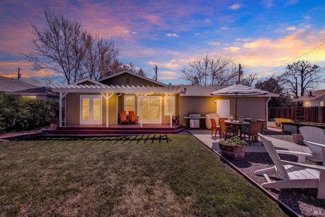 back of property featuring a lawn, a pergola, a patio, fence, and french doors