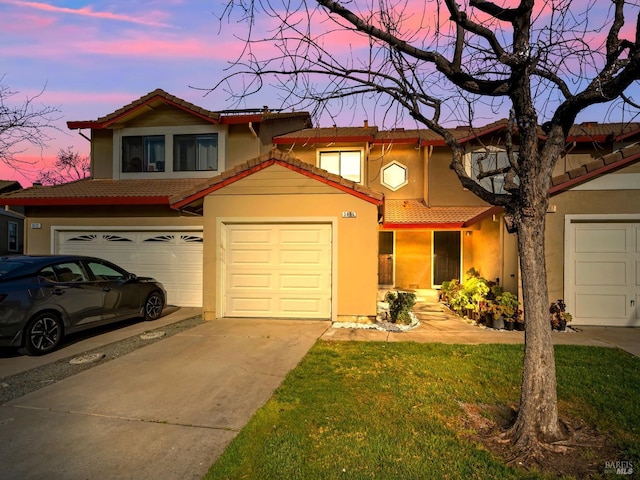 view of front of home featuring stucco siding, an attached garage, driveway, and a tile roof