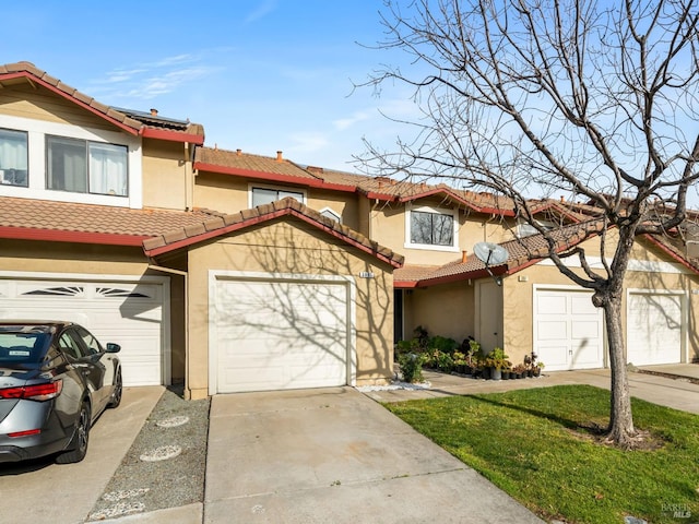 multi unit property featuring driveway, a tile roof, roof mounted solar panels, and stucco siding