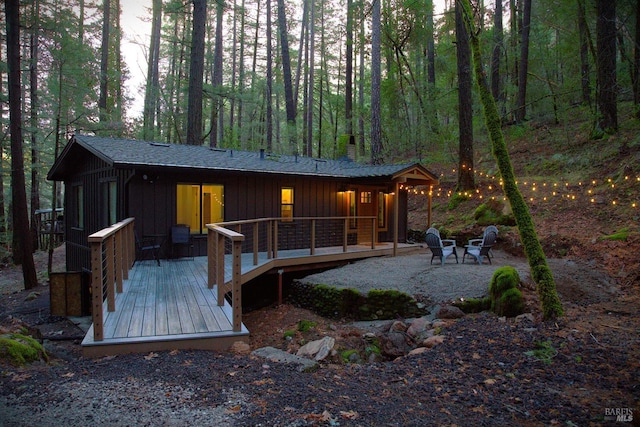 rear view of property with board and batten siding, a deck, and a chimney