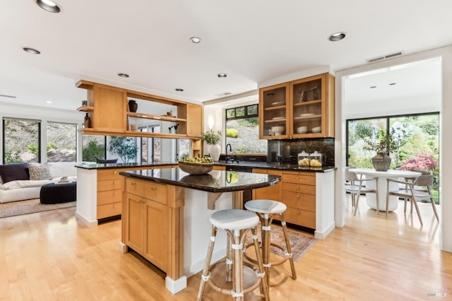 kitchen with open shelves, light wood-style floors, visible vents, and a sink