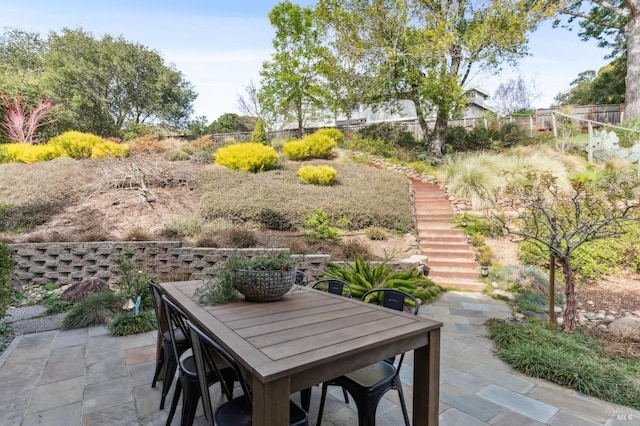 view of patio featuring outdoor dining space, stairway, and fence