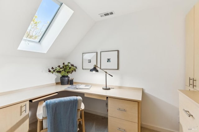 office area featuring vaulted ceiling with skylight, baseboards, visible vents, and built in study area