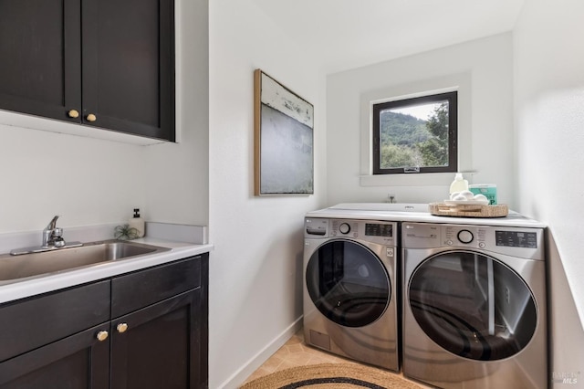 washroom featuring baseboards, light tile patterned floors, washer and dryer, cabinet space, and a sink