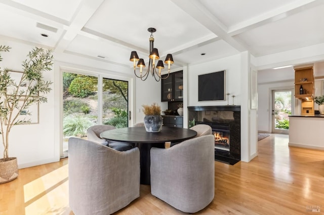 dining room with a fireplace with flush hearth, coffered ceiling, light wood-style floors, an inviting chandelier, and baseboards