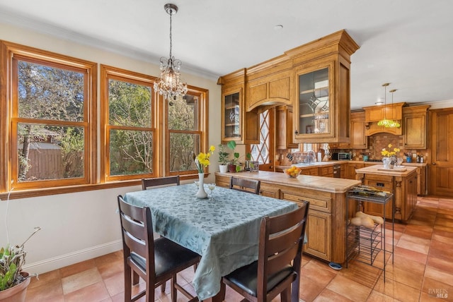 kitchen with a kitchen island, baseboards, decorative light fixtures, ornamental molding, and brown cabinets