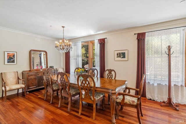 dining space featuring an inviting chandelier, crown molding, and wood finished floors