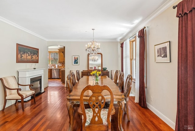 dining space featuring a glass covered fireplace, wood finished floors, and ornamental molding