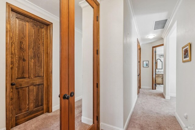 hall with crown molding, light colored carpet, visible vents, and baseboards