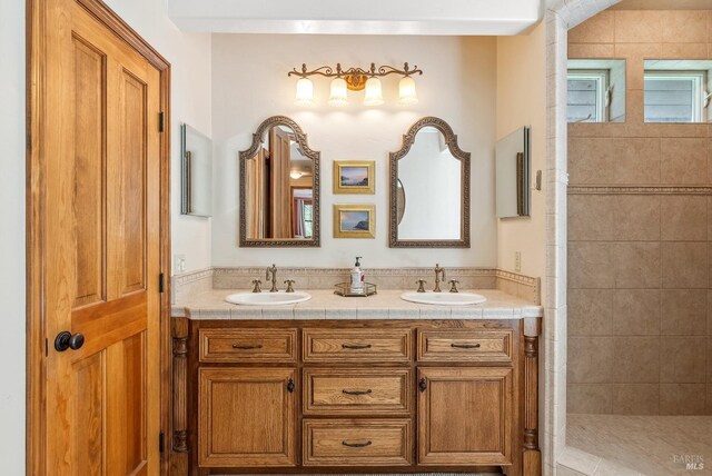 bathroom featuring double vanity, a walk in shower, and a sink