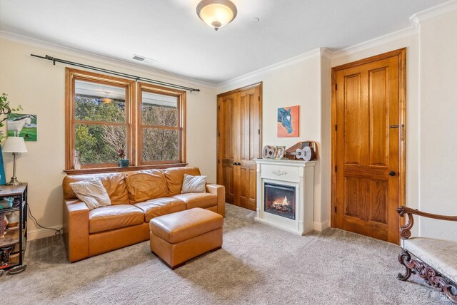 living area with light carpet, a glass covered fireplace, visible vents, and ornamental molding