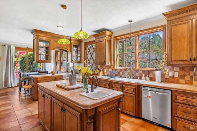 kitchen with tile countertops, dishwasher, and a sink