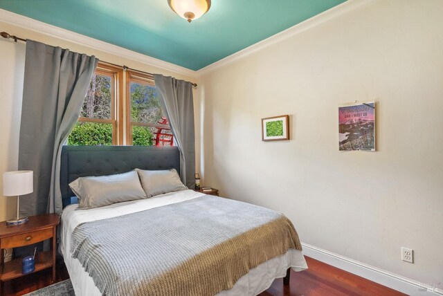 bedroom with crown molding, wood finished floors, and baseboards