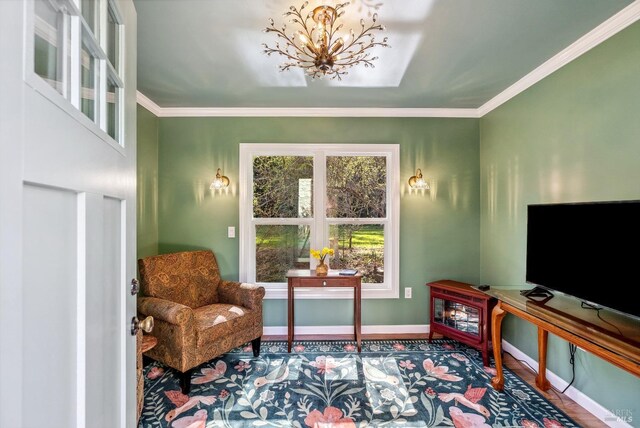 living area featuring baseboards, an inviting chandelier, wood finished floors, and crown molding