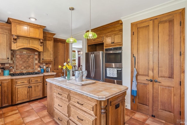 kitchen featuring tasteful backsplash, appliances with stainless steel finishes, tile counters, and brown cabinetry