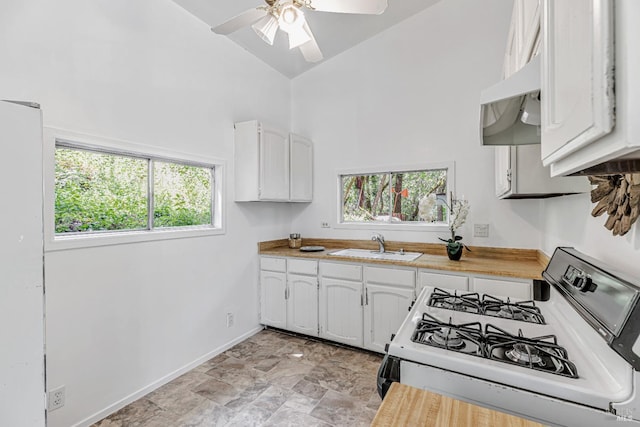 kitchen with white gas range oven, a sink, a wealth of natural light, and high vaulted ceiling