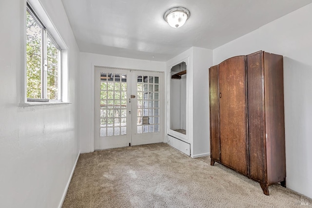 interior space with french doors, baseboards, multiple windows, and carpet flooring