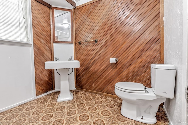 half bath with wood walls, baseboards, and toilet