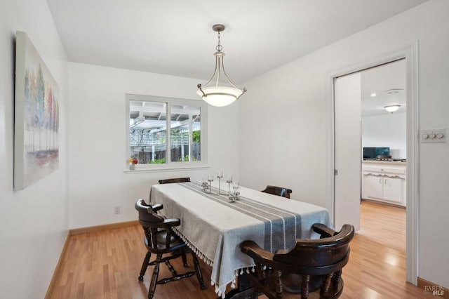 dining space featuring light wood-type flooring and baseboards