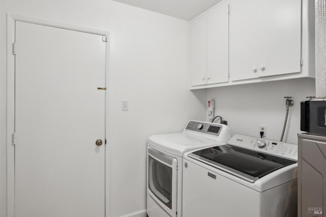 clothes washing area featuring cabinet space and washing machine and clothes dryer