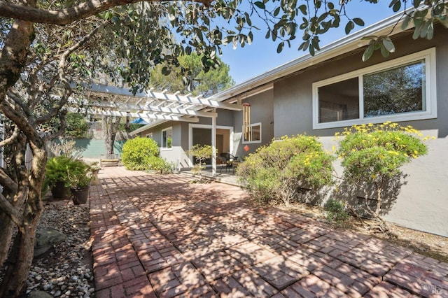 exterior space with stucco siding, a patio area, and a pergola