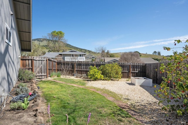 view of yard featuring a garden, a mountain view, and a fenced backyard