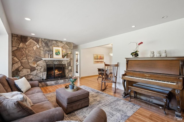 living area featuring a stone fireplace, recessed lighting, and wood finished floors