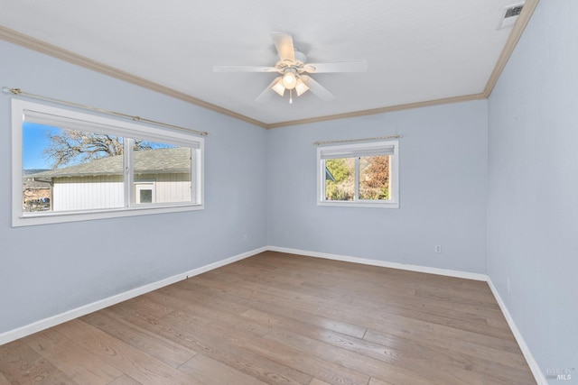 empty room featuring visible vents, crown molding, baseboards, wood finished floors, and a ceiling fan