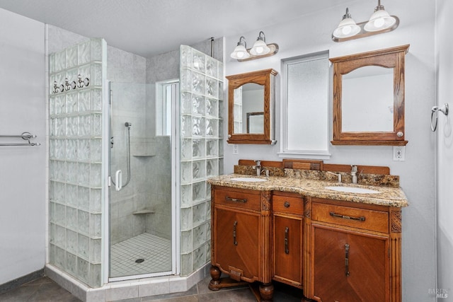 bathroom featuring a sink, double vanity, a shower stall, and tile patterned floors