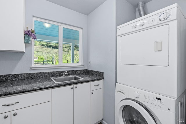 clothes washing area featuring cabinet space, stacked washing maching and dryer, and a sink