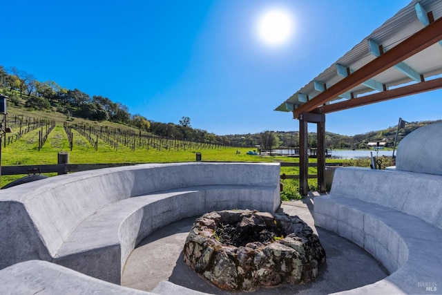 view of patio featuring a fire pit, a water view, and fence