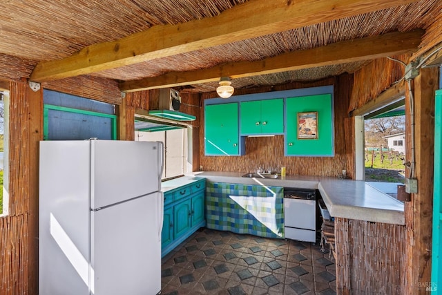 kitchen with white appliances, beam ceiling, a sink, light countertops, and wood walls