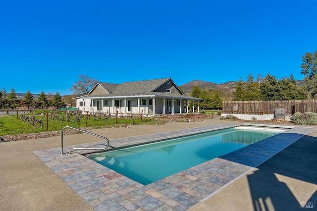 view of swimming pool with a patio area, a fenced in pool, a mountain view, and fence