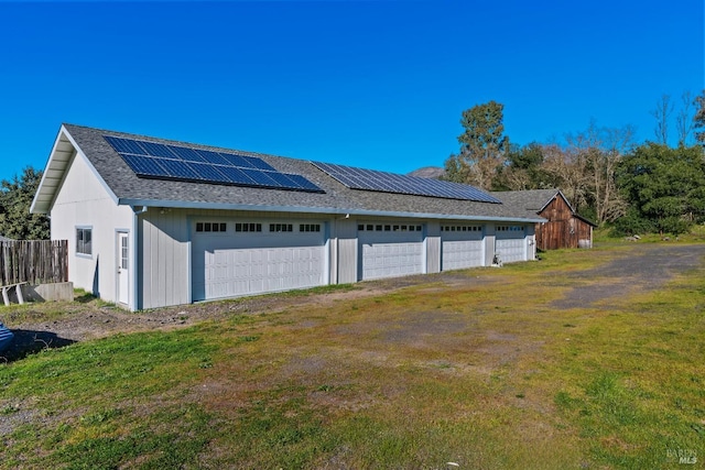 garage featuring fence and roof mounted solar panels