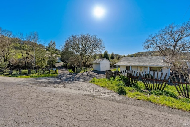 view of property exterior with an outdoor structure, a storage unit, and a fenced front yard