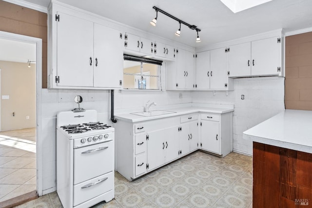 kitchen featuring white gas range, white cabinets, light countertops, and a sink