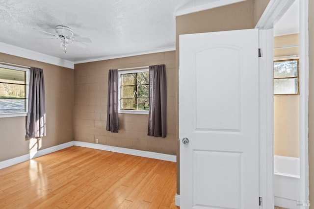 empty room featuring baseboards, light wood-style flooring, a ceiling fan, and ornamental molding