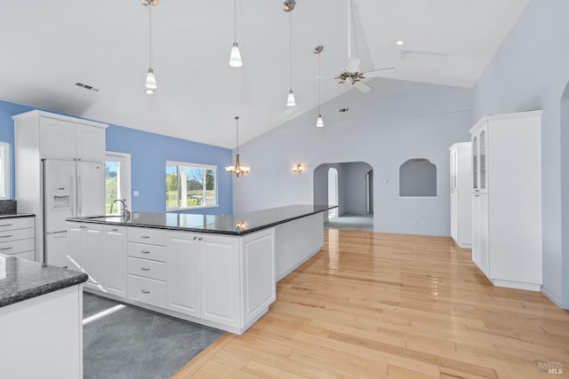 kitchen with visible vents, light wood-style flooring, white cabinetry, arched walkways, and white fridge with ice dispenser