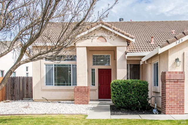 view of front of house with a tile roof, fence, and stucco siding