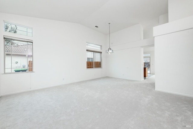 carpeted spare room featuring a notable chandelier, baseboards, and high vaulted ceiling