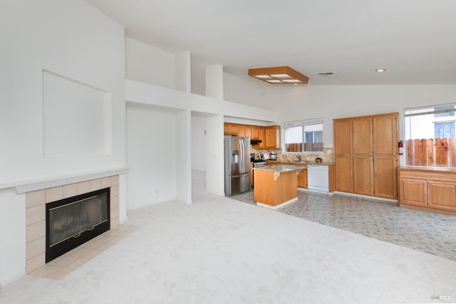 kitchen featuring visible vents, a kitchen island, stainless steel fridge with ice dispenser, a fireplace, and white dishwasher