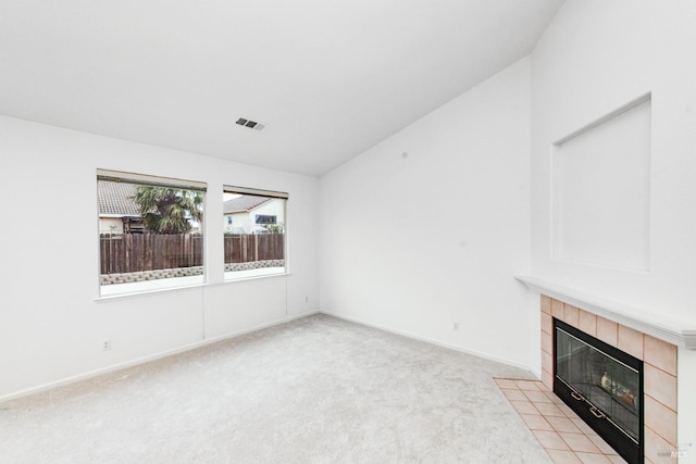 unfurnished living room featuring baseboards, visible vents, lofted ceiling, light carpet, and a tiled fireplace