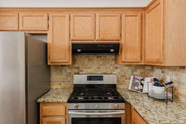 kitchen with light stone countertops, light brown cabinets, decorative backsplash, extractor fan, and appliances with stainless steel finishes