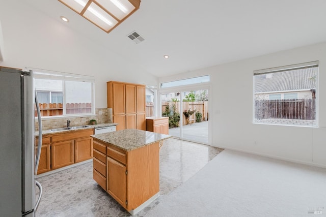 kitchen with visible vents, a sink, backsplash, a center island, and freestanding refrigerator