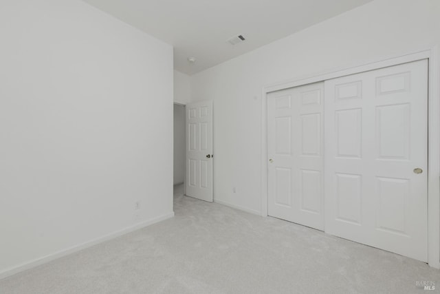 unfurnished bedroom with light carpet, visible vents, baseboards, and a closet